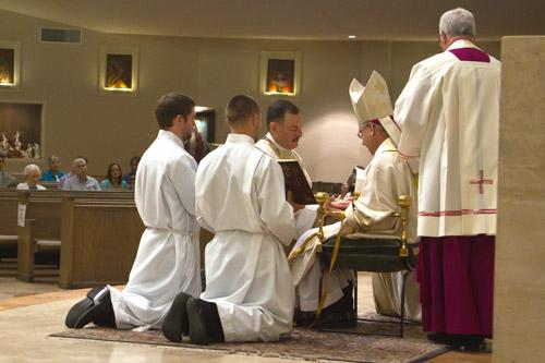After being invested with a stole and chasuble, Father George Sanders kneels before the bishop who anoints his hands with chrism oil. Bob Ocken photo