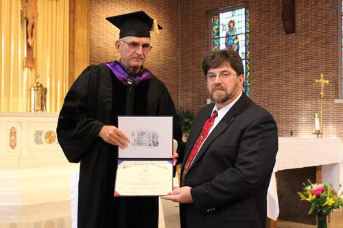 Dr. Ron Faulk (left) presents Clark Wilkinson his diploma from St. Gregory the Great University. Wilkinson, a member of Our Lady of the Holy Souls in Little Rock, earned a bachelor's degree in theology. Dwain Hebda photo