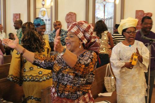 Josephine Wakwe throws open her arms in greeting during the sign of peace. The particular brand of joy North Little Rock Igbo parishioners express during their native-language Mass reflects the joy of being in God’s presence. Dwain Hebda photo

