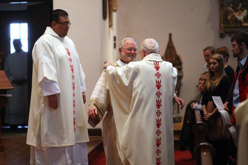 Pastor Father Henry Mischkowiuski helps Deacon Jack Sidler put on his stole and dalmatic. Deacon Juan Guido (left) looks on.