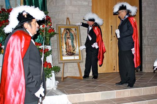 Luis Hernandez (left), Bob Maloney and Miguel Andradi, members of the Knights of Columbus, install the image of Our Lady of Guadalupe at the altar at St. Vincent de Paul Church in Rogers. Alesia Schaefer photo