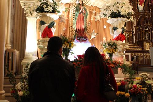 Following Dec. 12 morning Mass, a young couple prays silhouetted against the brightly lit shrine to Our Lady of Guadalupe set up at St. Edward Church in Little Rock. Dwain Hebda photo