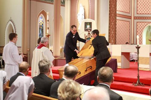 Funeral home employees close the lid of Bishop McDonald's coffin under the watchful eye of Msgr. Francis I Malone, pastor of Christ the King Church in Little Rock. Bob Ocken photo