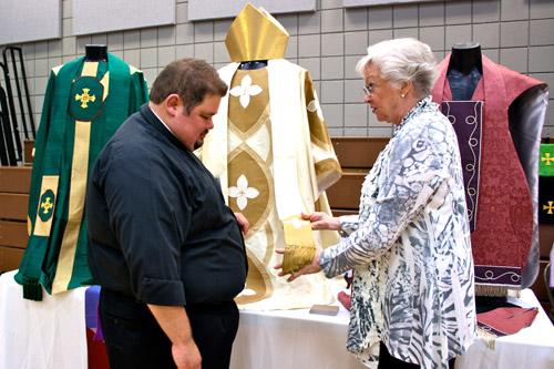 Father Shawn Wesley, pastor of St. Joseph's in Fayetteville, looks over vestments offered by Ruth Davis, owner of Holy Orders Liturgical Threads, one of seven vendor booths. Alesia Schaefer photo