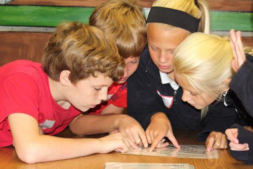 Holy Souls sixth-grade classmates consult the periodic table of the elements during an exercise in the CHI St. Vincent Infirmary pharmacy. They are Thomas Fitz (left), Henry Handley, Olivia Napier and Hattie Cooper. (Dwain Hebda photo)