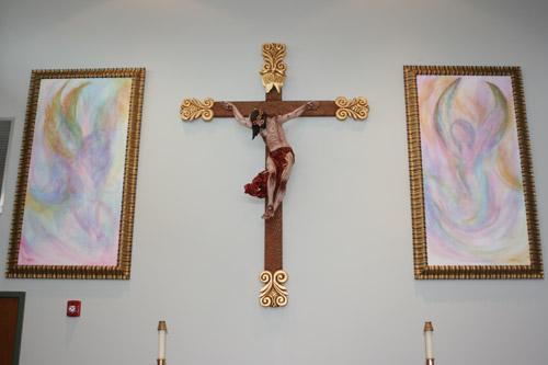 A crucifix by Mexican artist Juan Campos hangs in between art donated by Kat Friend, the niece of Msgr. Scott Friend, vocations director for the diocese. The angel paintings were in memory of her mother, Betty Friend. (Aprille Hanson)
