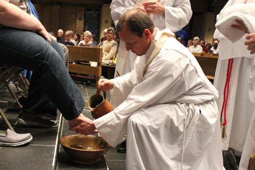 Father Erik Pohlmeier, pastor of Our Lady of the Holy Souls Church in Little Rock, washes the feet of a parishioner as a capacity congregation looks on during Holy Thursday Mass, April 2. (Dwain Hebda) 