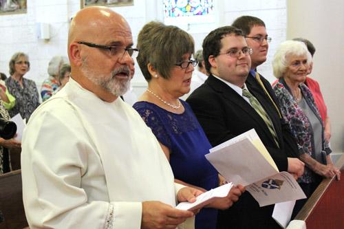 Deacon Norman McFall sings the opening hymn at his Ordination to the Diaconate Mass May 20 at St. Joseph Church in Pine Bluff. His wife, Laura and son Samuel are to his left. (Dwain Hebda photo)
