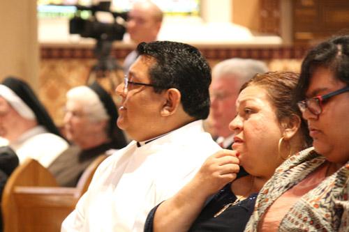 Mario Jacobo sits in the front pew with his mother, Maria Urtes of Calhoun, Ga., at the beginning of Mass. (Malea Hargett photo)