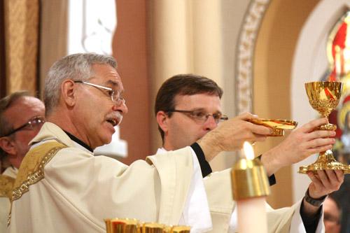 Deacon Taryn Whittington holds up the chalice during his ordination Mass. (Malea Hargett photo)