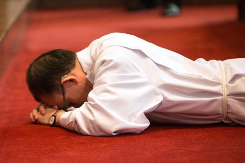 During the Litany of Supplication, Joseph Chan lays prostrate before the altar.  (Karen Schwartz photo)