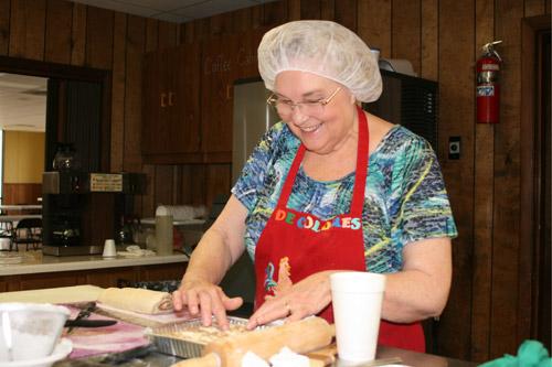Shelia Bednar makes sure the made-from-scratch cinnamon rolls fit just right in the baking pan. She is one of the original Slovak Bakers, which started in the late 1990s. (Aprille Hanson photo)