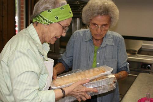 Roberta Uhiren (left), dubbed “Mother Superior” by the Slovak Bakers, hands off baked goods to Francis Chudy, the oldest member at 89 years old. (Aprille Hanson photo)