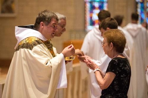 Newly ordained Father Patrick Boland gives Communion to his mother, Catherine Boland, during Mass June 20 at Subiaco. (Karen Schwartz photo)