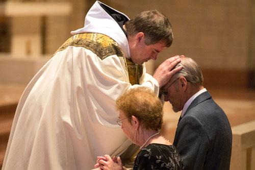 Newly ordained Father Patrick Boland, OSB, blesses his father, James Boland, after the ordination Mass June 20 in St. Benedict Church at Subiaco Abbey. (Karen Schwartz photo)