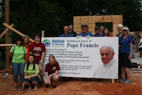 Volunteers from the Pope Francis House worksite, including those from St. Jude the Apostle Church in Jacksonville, stop for a quick photo by the Pope Francis sign. (Aprille Hanson) 