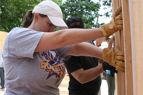 Christine Appleton, a member of the Cathedral of St. Andrew in Little Rock, holds a wall steady at the Pope Francis House. She worked along with her 16-year-old son Jack, part of the Cathedral’s Catholic Youth Ministry group. (Aprille Hanson) 