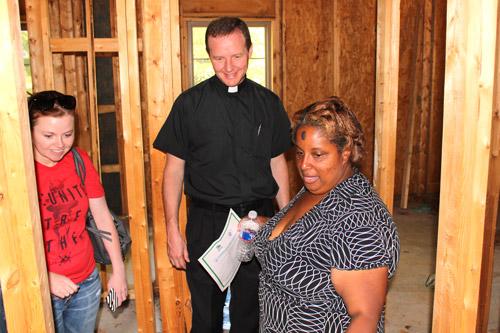 Regina Goynes leads visitors through her new home, including Father Erik Pohlmeier of Our Lady of the Holy Souls Church, who blessed the house during dedication ceremonies Sept. 26 in Little Rock. (Dwain Hebda photo)