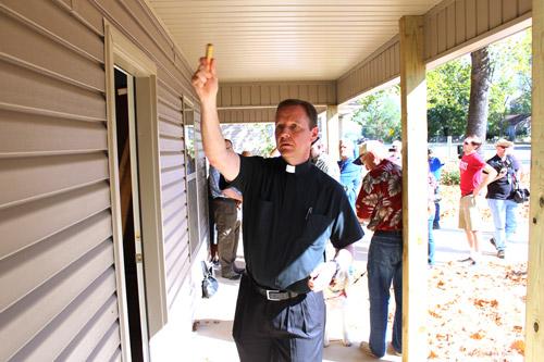 Father Erik Pohlmeier, pastor of Our Lady of the Holy Souls Church in Little Rock, blesses Pope Francis House with holy water during dedication cere-monies Sept. 26. The Habitat for Humanity project was built primarily by Catholic volunteers. (Dwain Hebda photo)
