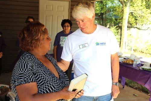 Bill Plunkett, CEO of Habitat for Humanity of Pulaski County, presents Regina Goynes with a Bible as a housewarming present during dedication of the Pope Francis House in Little Rock Sept. 26. (Dwain Hebda photo)
