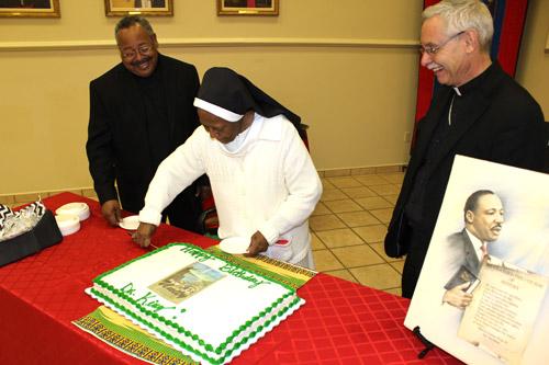 At a dinner following Mass, Sister de Porres cuts Dr. King's birthday cake under the gaze of Father Warren Harvey (left) and Bishop Anthony B. Taylor. (Dwain Hebda photo)