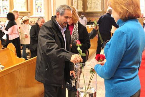 A man places a rose in a vase during the offertory. Individuals who had lost a child for any reason were given a rose and asked to bring it up as a remembrance. (Dwain Hebda photo)