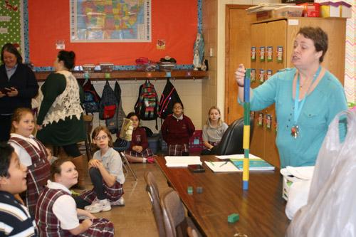 St. Theresa second-grade teacher Amanda Williams explains how stacking blocks with no regard to the structure can easily cause them to fall down. The second, third and fourth grade students were challenged to build the tallest tower with only toothpicks and gumdrops on Jan. 25. (Aprille Hanson photo) 