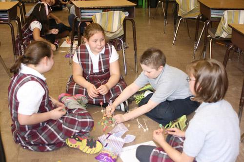 Second grader Andrew Gangluff works on building the tower while his group discusses their design. Others pictured are: Olivia Sutton, third grade (left); Sheyla Green, third grade; and Anna Williams, fourth grade. (Aprille Hanson photo)