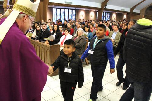 Bishop Anthony B. Taylor shakes a young catechumen's hand during the Feb. 14 celebration of the Rite of Election for central Arkansas. (Dwain Hebda photo)