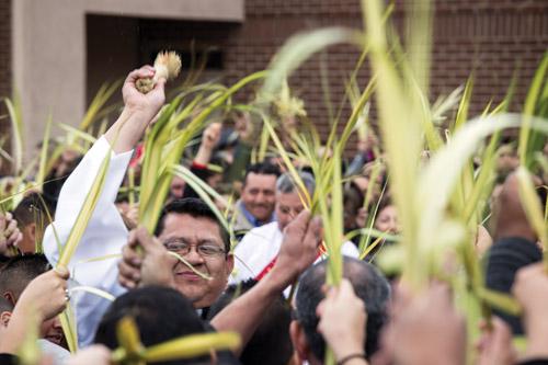 Seminarian Deacon Mario Jacobo blesses the palms outside before Mass at St. Raphael Church in Springdale on Palm Sunday March 20. (Travis McAfee photo)
