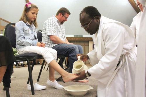 Pastor Father John Wakube, AJ, washes the feet of second-grader Anna Dearworth during Holy Thursday Mass at Immaculate Conception Church in North Little Rock. Anna was one of 12 people to have their feet washed. (Dwain Hebda photo)