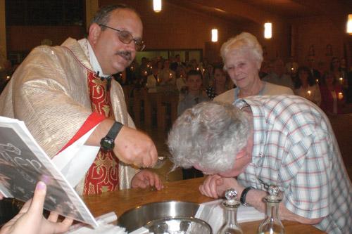 Father Norbert Rappold, pastor at St. Peter the Fisherman Church in Mountain Home, baptizes Ronald Wayne Martin, 75, as his wife Dorothy Martin watches during Easter Vigil Mass March 26. Eleven Catholics joined St. Peter Church. (Aprille Hanson photo)