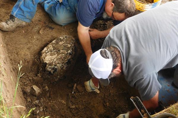 Archaeologists Jared Pedworth (left) and Mike Evans work to remove the charred remains of what they believe could be a 475-year-old cross Tuesday, April 19. The wood is currently being testing through radiocarbon dating and tree ring analysis. (Jessica Crawford photo, The Archaeological Conservancy)