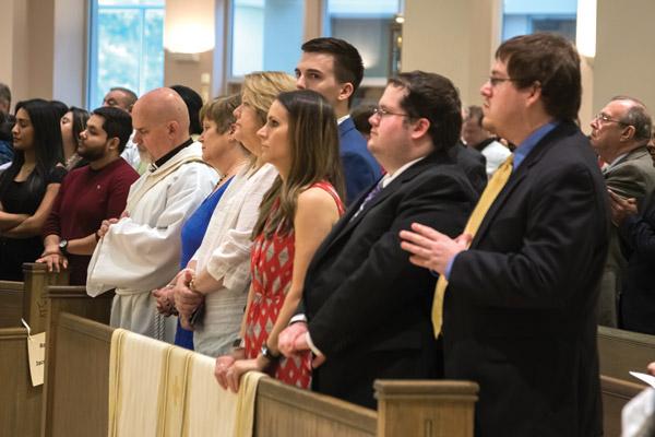 Norman McFall, his wife Laura, their son Samuel (second from right), family and friends listen to the bishop at the beginning of the ordination Mass. McFall was ordained through a special provision from the Vatican. (Bob Ocken photo)