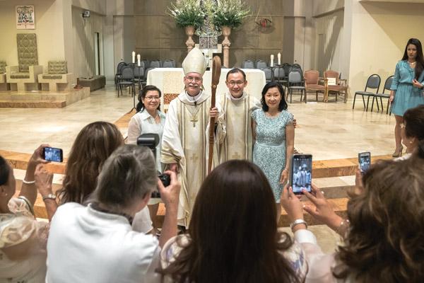 Family and friends snap photos after Mass of Father Joseph Chan with Bishop Taylor and his sisters Inmaculada Chan-Espanto (left) and Raquel Tan Chan. (Bob Ocken photo)