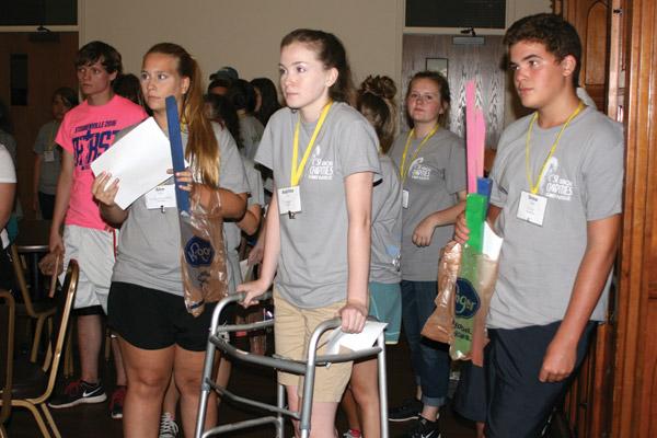 With only their allotted “supplies” and assigned character for the journey, Allee Haynes, 18, of Our Lady of the Assumption in Booneville (front, left), Avanlea Furr, 17, of St. Agnes in Mena and Drew Capps, 14, of St. Paul in Pocahontas, prepare to set out toward hoped-for safety. (Aprille Hanson photo)
