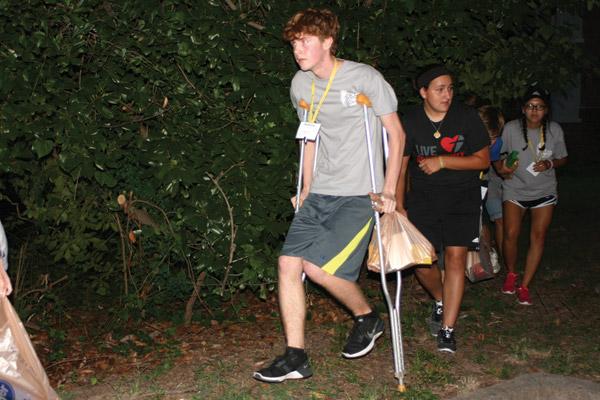 Andrew Eveld, 16, of Sacred Heart Church in Charleston, stumbles over rough ground on the crutches needed by his assigned character as he avoids the pavement and a chance of capture, followed by Nicole Salman, 18, of St. James Church in Searcy and Jasmine Rico, 17, of St. Edward Church in Little Rock. (Aprille Hanson photo)