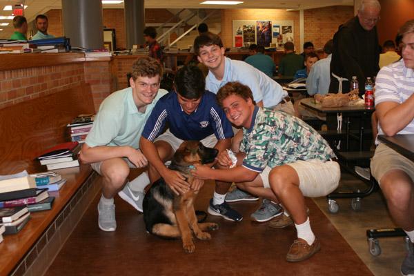 Titus enjoys lunchtime with students, happily taking on the role of “clean-up crew” looking for scraps. Pictured are seniors Duncan Diaz (left), Joseph Enderlin, Jack Storey and Seth Parham. (Aprille Hanson photo) 