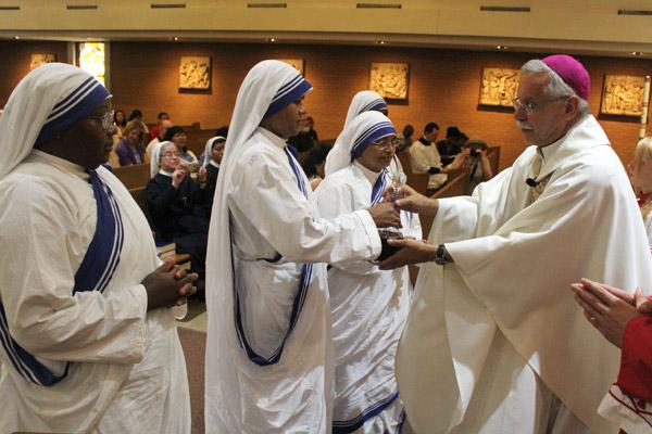 Sister Maria Jyoti hands Bishop Anthony B. Taylor the decanter of wine flanked by her fellow Missionaries of Charity Sisters during Mass for St. Teresa of Kolkata Sept. 4. (Dwain Hebda photo)