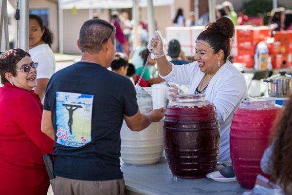 Susan Cruz and J. Carmen Perez pay tickets to receive a glass of "horchata" a popular cinnamon flavored rice-based drink during Summerfest at St. Raphael in August. (Travis McAfee photo) 