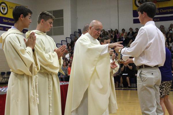 Msgr. Lawrence Frederick, CHS rector, accepts the gifts during the annual Ring Mass held at Catholic High School in Little Rock. (Dwain Hebda photo)