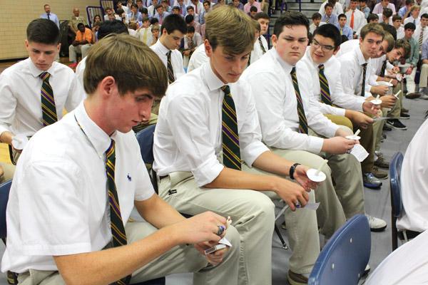 Ring fingers newly adorned, CHS seniors light candles to close the annual Ring Mass with a hymn and the Alma Mater. Preston Wilson (left) lights his candle and Matthew Noonan looks on. (Dwain Hebda photo)