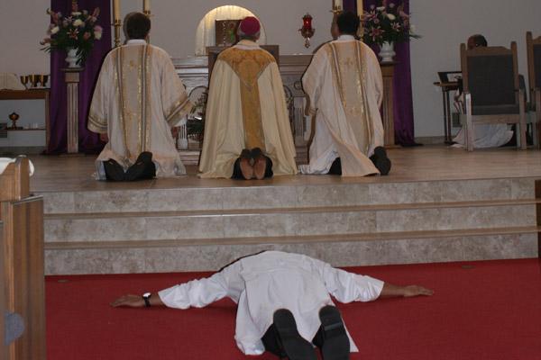 Nelson Rubio prostrates himself during the litany of saints at his diaconate ordination Dec. 17 while Bishop Anthony B. Taylor and Deacons Martin Siebold (left) and Ramses Mendieta pray. (Aprille Hanson photo)