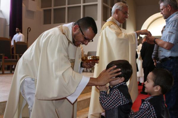 Deacon Rubio blesses a young boy during communion at Sacred Heart of Jesus Church in Hot Springs Village. (Aprille Hanson photo)