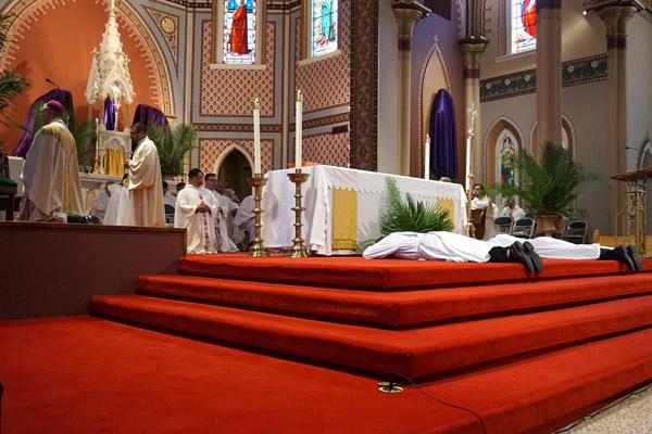 Deacons Tuyen Do and Jeff Hebert lay prostrate during the Litany of Saints. (Aprille Hanson photo) 
