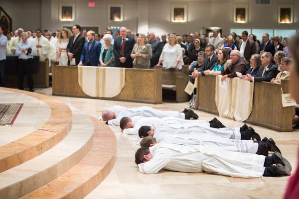 Fathers William Burmester, Stephen Hart, Ramsés Mendieta, Martin Siebold and Luke Womack lay prostrate in front of the altar at Christ the King Church in Little Rock as congregants sing the litany of the saints. (Travis McAfee photo)