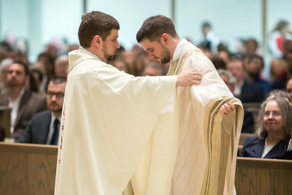 Father Andrew Hart, pastor at St. Thomas Aquinas University Parish in Fayetteville, vests his brother, Father Stephen Hart, at his priestly ordination May 27. (Travis McAfee photo)
