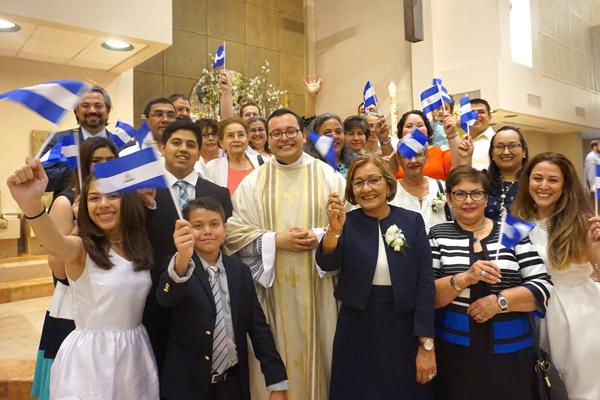 Father Ramsés Mendieta stands with his family, waving flags from his native Nicaragua following his priestly ordination May 27 at Christ the King Church in Little Rock. (Malea Hargett photo)