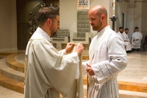 Deacon Stephen Hart, who was ordained a priest May 27, assists Deacon Patrick Friend with his stole and dalmatic. (Bob Ocken photo)