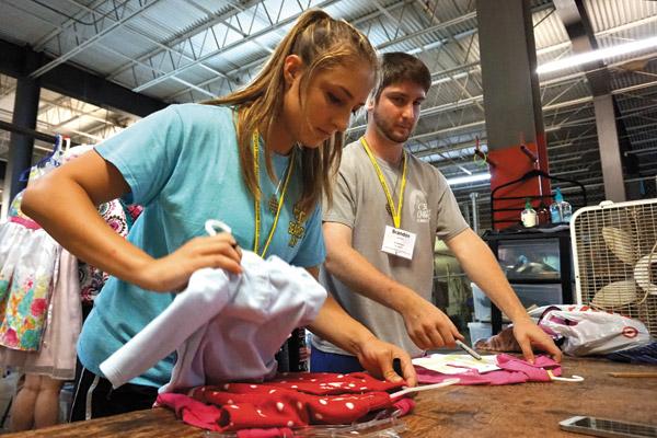 Chloe Ledbetter, 18, of St. John Church in Hot Springs, sorts children’s clothes at the Little Rock Compassion Center thrift store warehouse with Brandon Locknar, 18, of St. Boniface Church in Fort Smith. (Aprille Hanson photo) 
